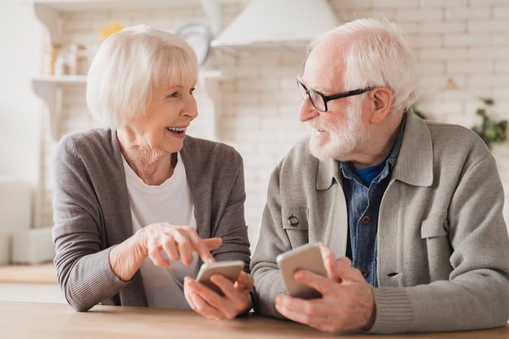 older couple looking at phones and smiling